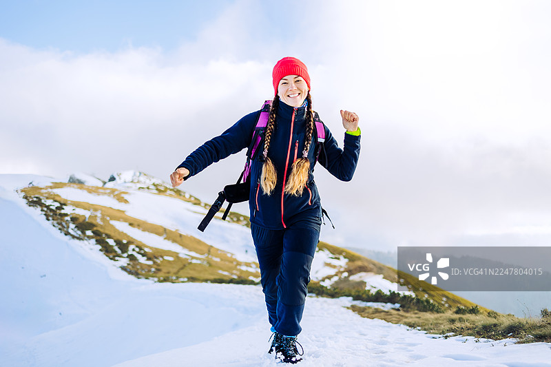 快乐的女人在冬天雪山徒步图片素材