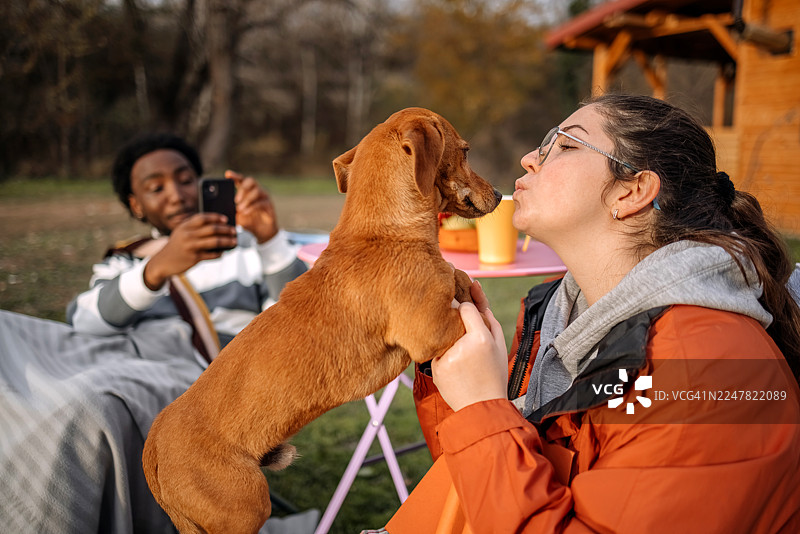秋日暖阳下，人们在小屋前放松，并与宠物玩耍图片素材
