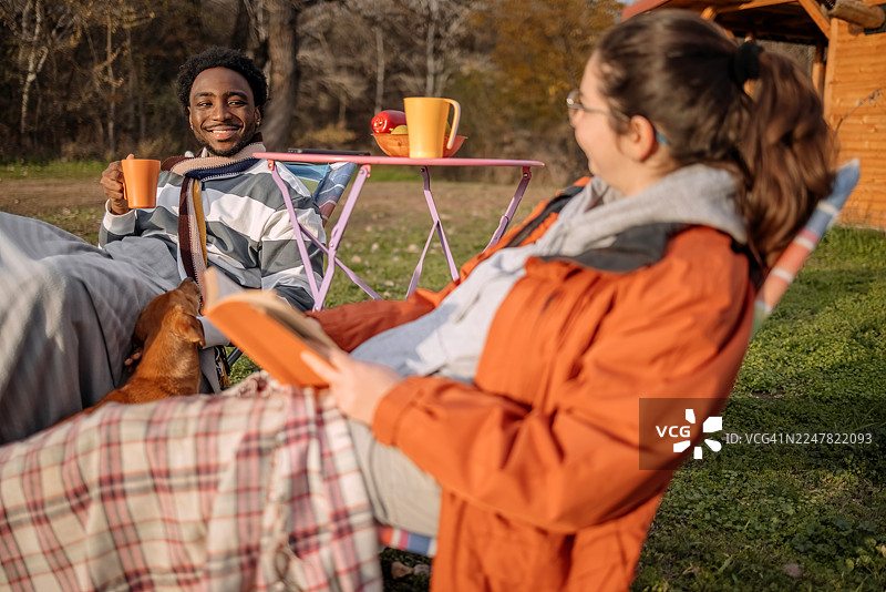 秋日暖阳下，人们在小屋前放松，并与宠物玩耍图片素材