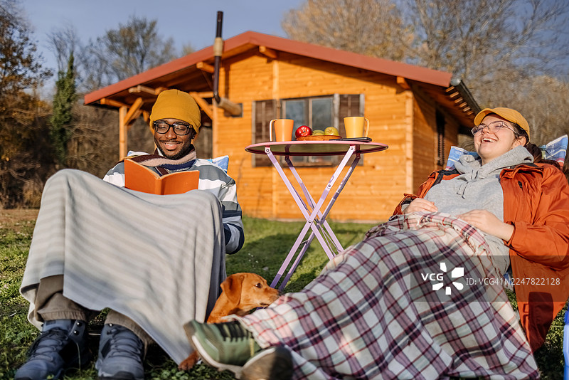 秋日暖阳下，人们坐在小屋前悠闲放松图片素材