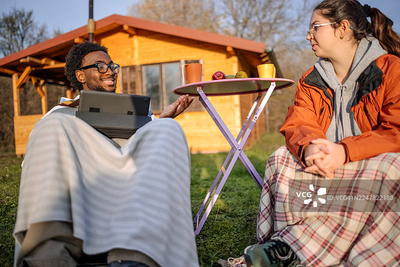 秋日晴朗的一天，人们坐在小屋前放松。图片素材
