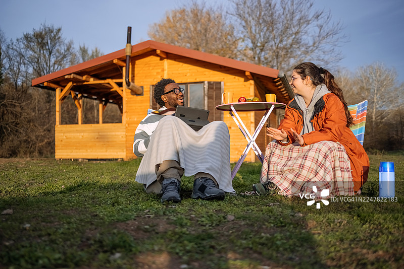 秋日暖阳下，人们在小屋前悠闲地坐着图片素材