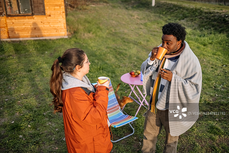 秋日暖阳下，人们站在小屋前悠闲交谈图片素材