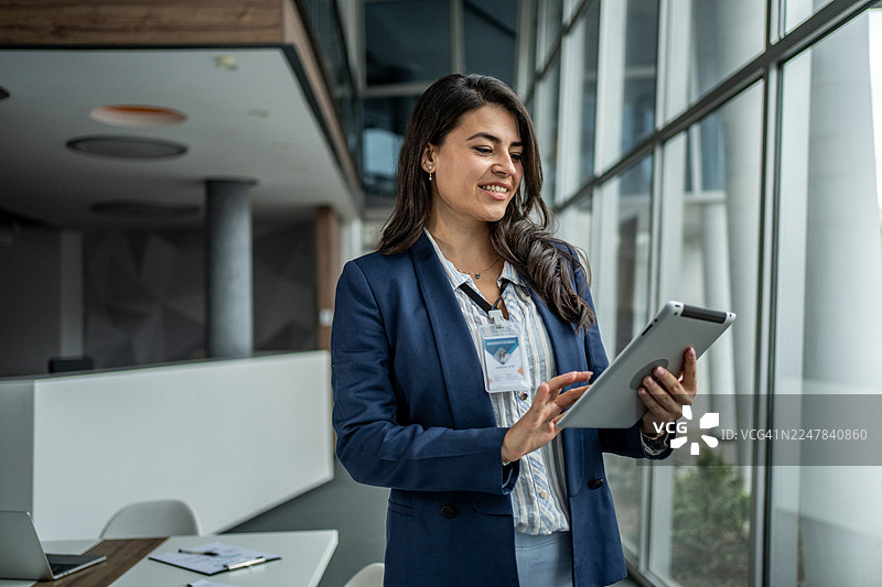 自信的女商人在现代办公室使用数码平板电脑图片素材