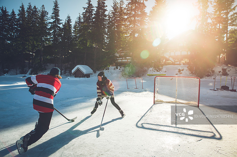 年轻男子在惠斯勒的池塘上打冰球图片素材