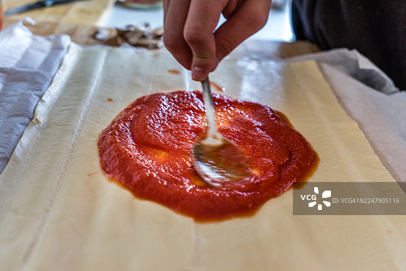 在披萨饼皮上涂抹番茄酱图片素材