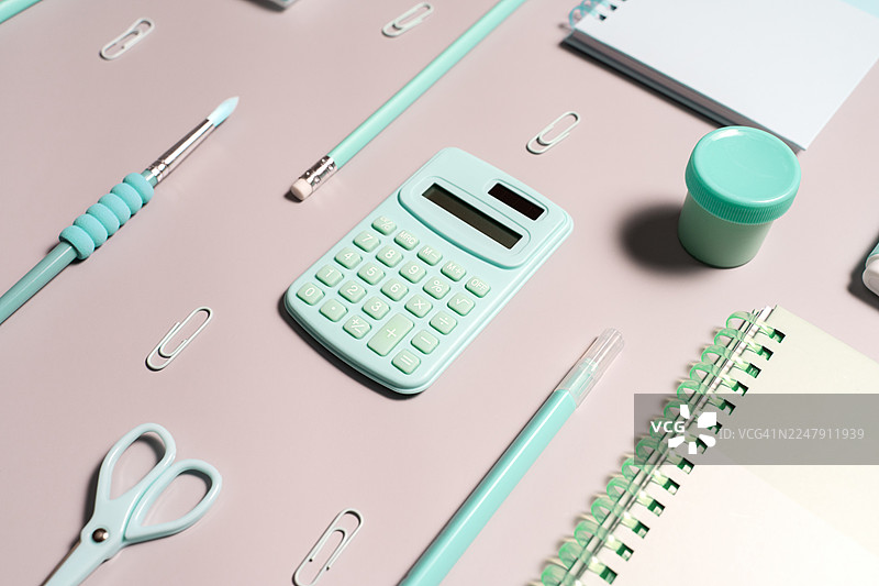 粉彩薄荷绿书桌布置，配有计算器、笔记本、剪刀和文具图片素材