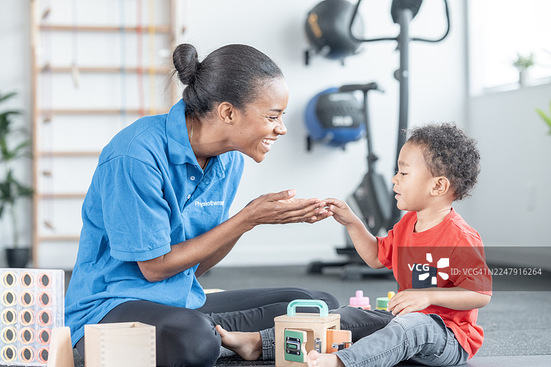 黑人女物理治疗师在治疗过程中与快乐的孩子互动，营造寓教于乐的环境图片素材