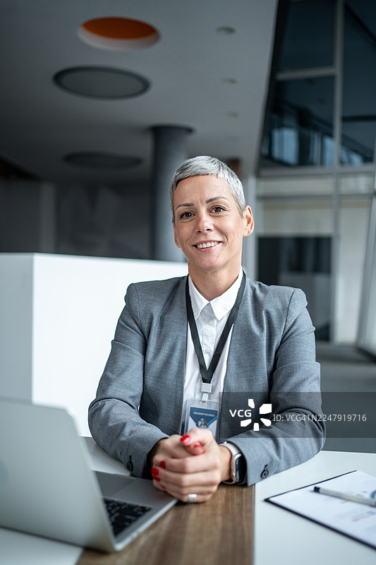 自信的女商人坐在办公桌前微笑图片素材