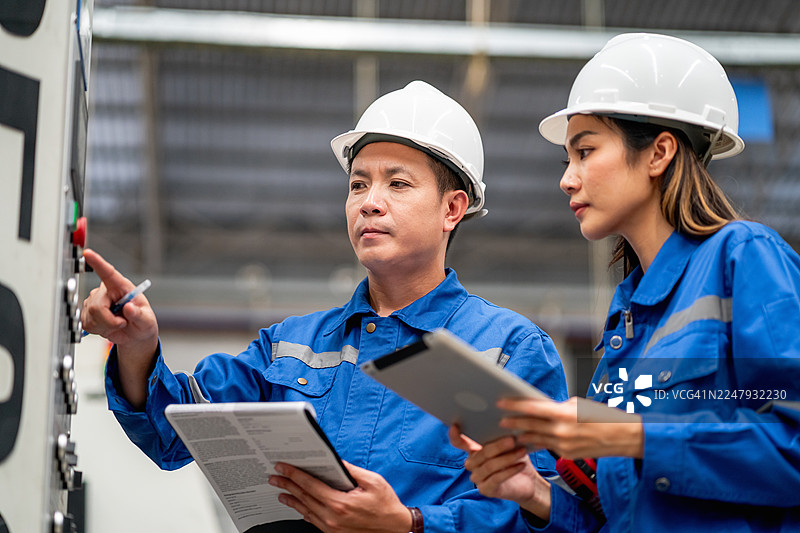 工程师在自动化工厂共同操作工业控制系统图片素材