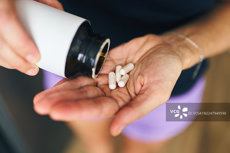 一人从药瓶中倒出白色药丸到张开的手中，医疗保健和药物概念图片素材