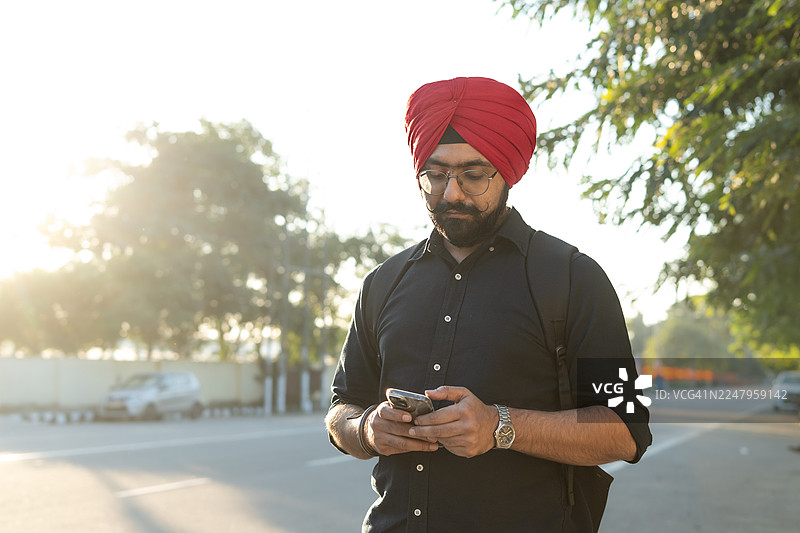 年轻的印度男子在户外使用手机。图片素材