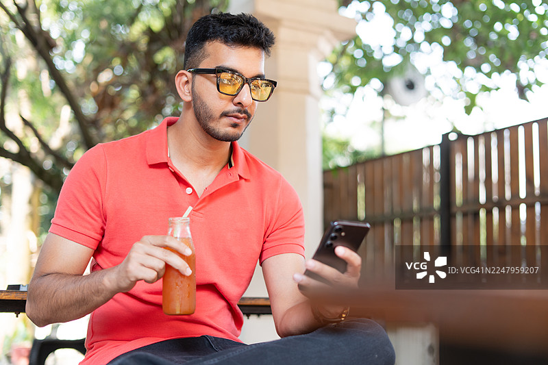 年轻的印度男性在户外使用手机。图片素材