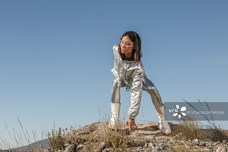 身着银色套装和未来感眼镜的年轻亚洲女性在阿尔梅里亚的岩石地形上摆姿势图片素材