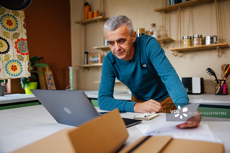 中年男子使用笔记本电脑进行网上银行操作图片素材