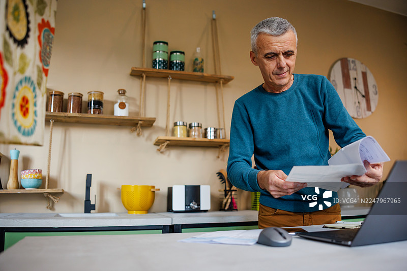 中年男子在厨房查看账单图片素材