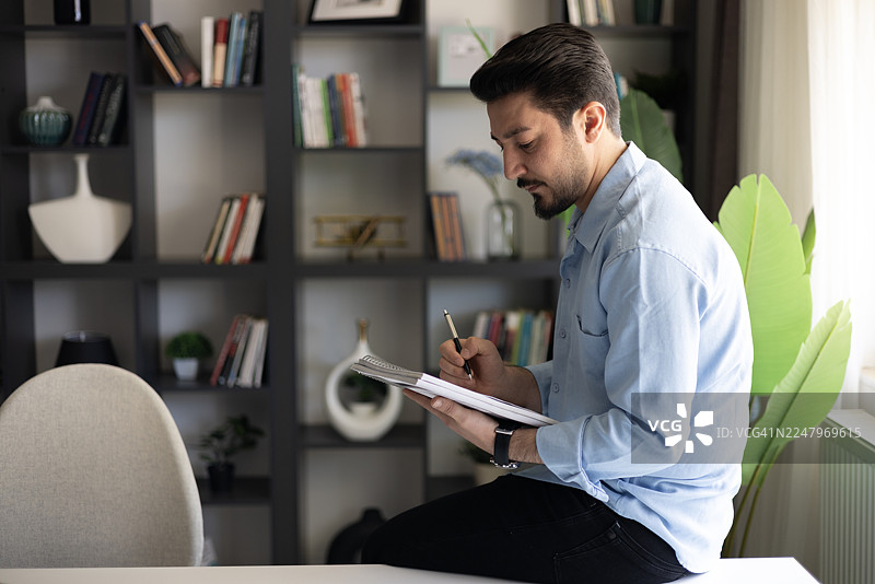 男人在书桌前写笔记本图片素材