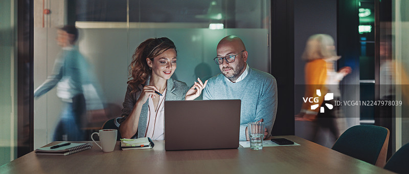 一对商务人士在办公室深夜使用笔记本电脑工作图片素材