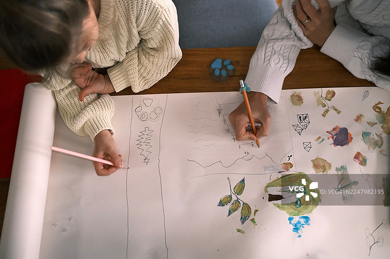 孩子们一起在一张大纸上用铅笔和颜料绘画，创意家庭艺术图片素材