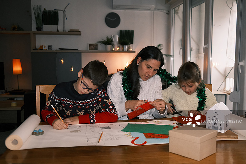 家庭手工之夜：父母与孩子在家制作圣诞贺卡，灯光温馨图片素材
