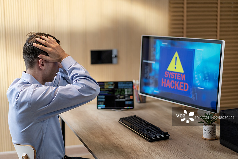 因网络欺诈导致电脑系统被黑客入侵，男子显得担忧、震惊且压力巨大图片素材
