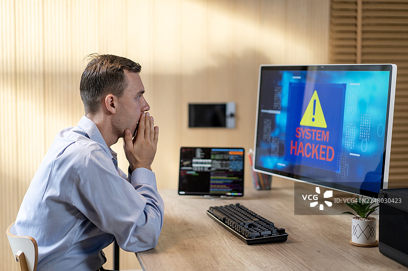 网络诈骗导致电脑系统被黑客入侵，男子忧心忡忡，表情震惊而压力巨大。图片素材