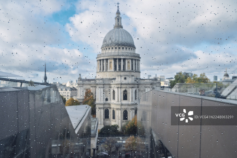 透过沾有雨滴的湿润玻璃看到的圣保罗大教堂圆顶和伦敦城市景观图片素材