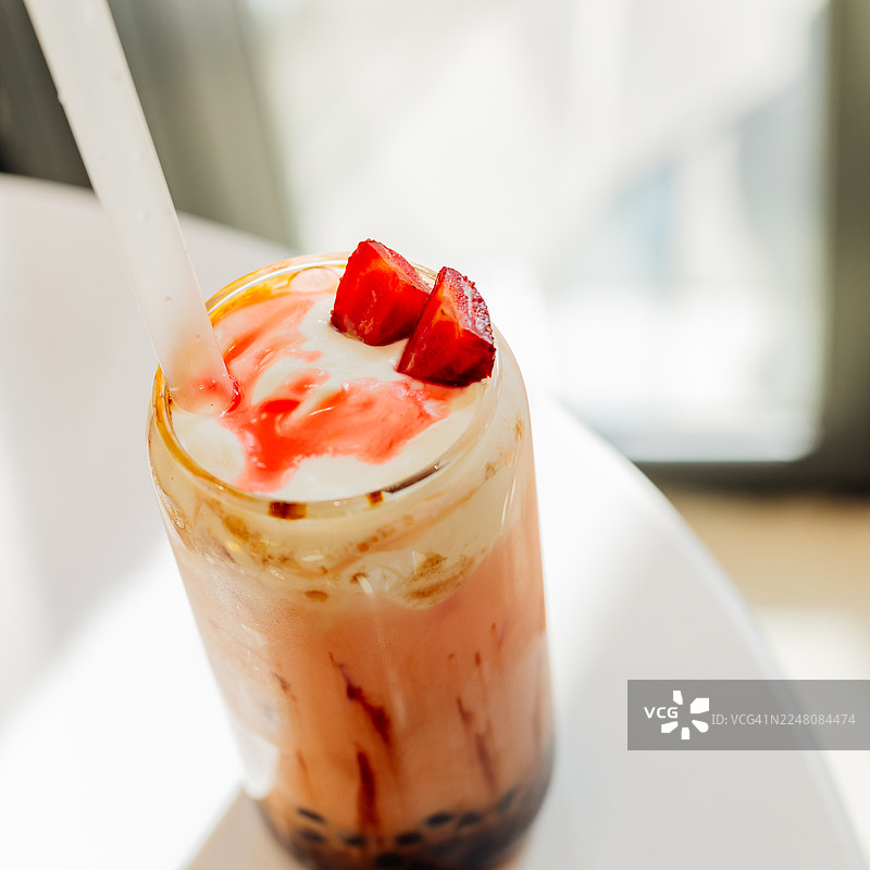 高脚杯中奶油草莓珍珠奶茶，配有木薯珍珠和鲜奶油图片素材
