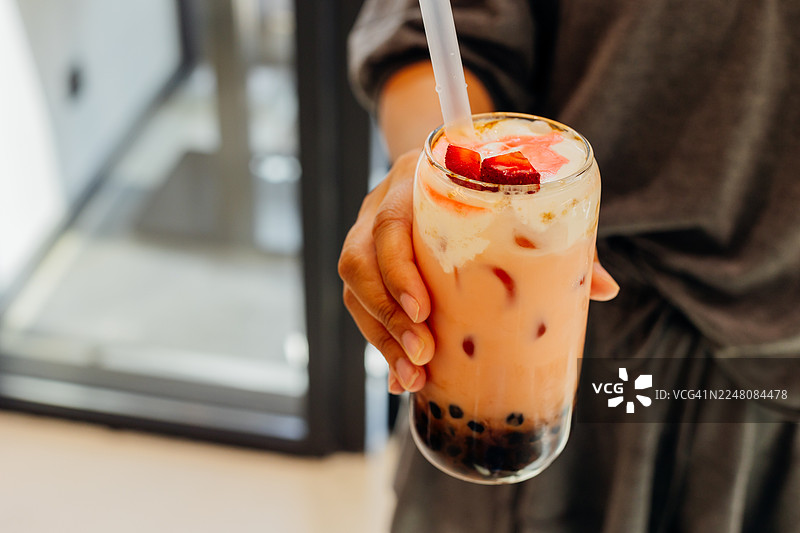 手拿桃子草莓冰块和木薯珍珠的玻璃杯珍珠奶茶图片素材