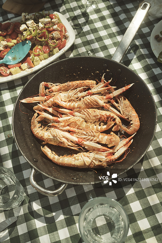 野餐桌上放着锅里烹饪好的小龙虾和新鲜的沙拉图片素材