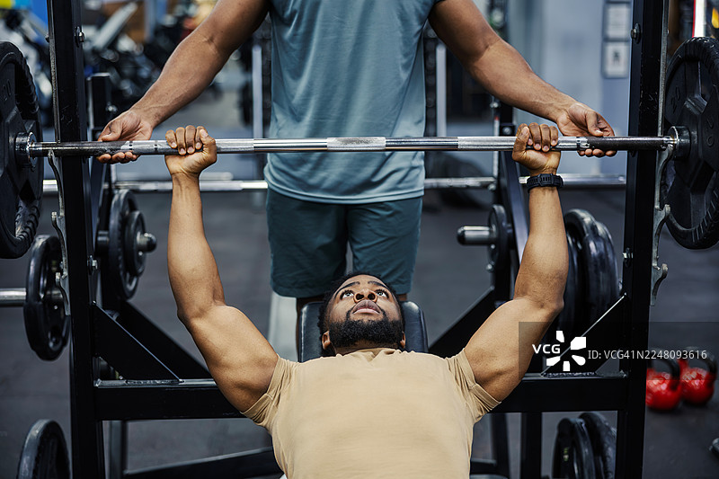 年轻男子在健身房接受保护者指导训练图片素材