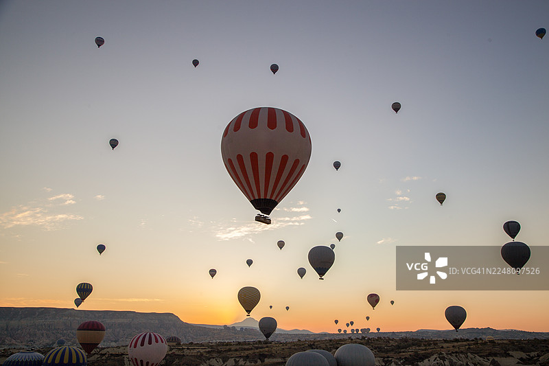 热气球在日出时分升起于卡帕多奇亚，这是一个受欢迎的旅游目的地图片素材