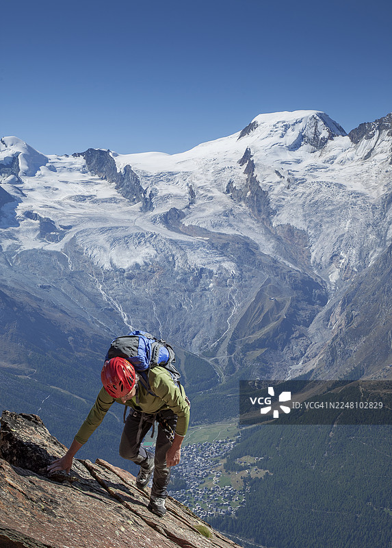 一位年长的登山者正在攀登一座多岩石的山峰并到达顶峰。图片素材