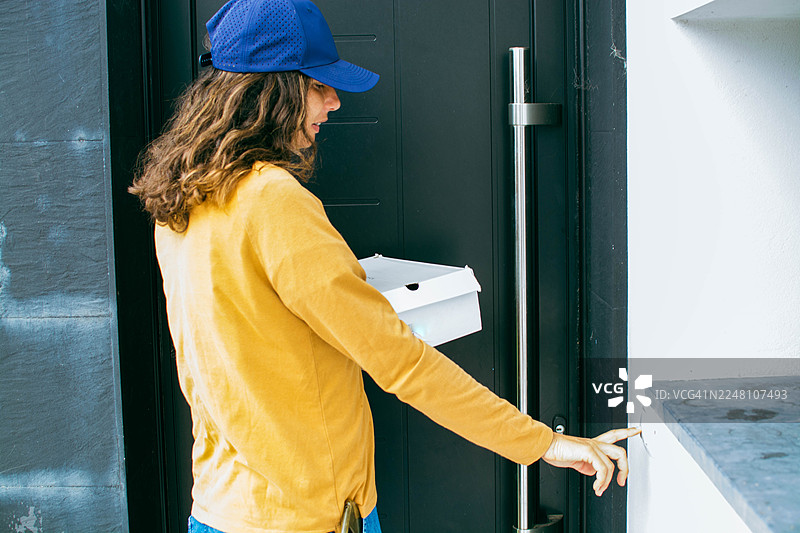 送货员在按门铃，同时手里拿着包裹图片素材