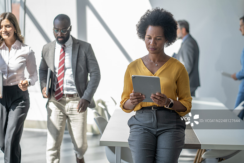 忙碌的办公室里，一位专注的女商人在使用数码平板电脑图片素材