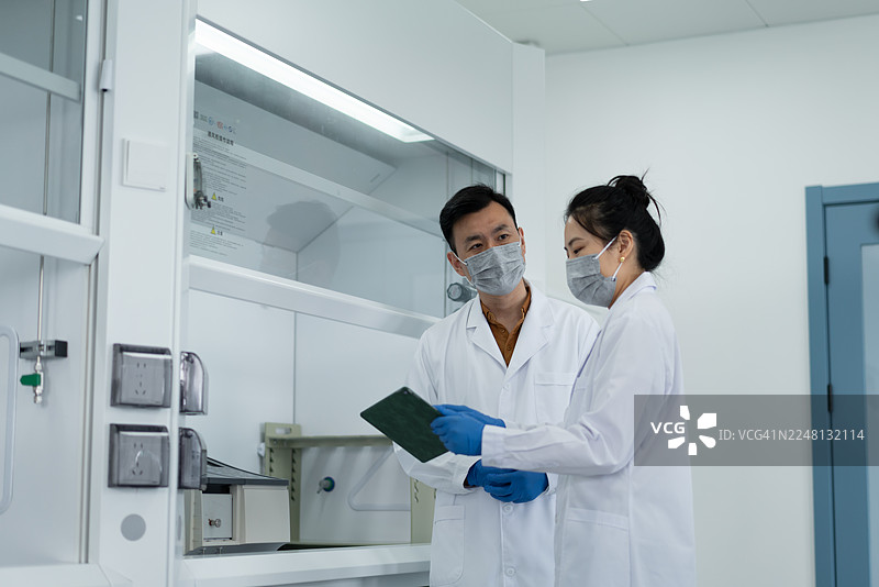 研究人员在实验室中使用数码平板电脑分析实验数据，以提高工作效率。图片素材