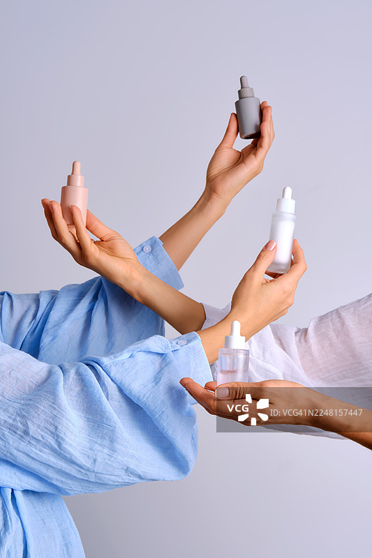 多位女性的手展示着小瓶的化妆品精华液图片素材