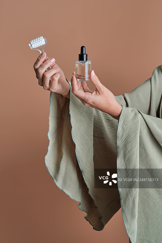 女子手持护肤精华和面部滚轮图片素材