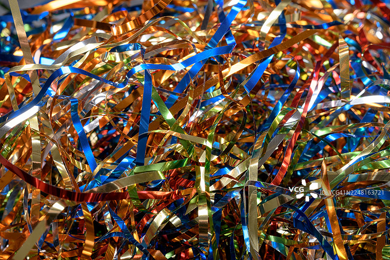 色彩鲜艳的金属彩带，以鲜艳的红、绿、金和蓝色调构成了抽象的背景，营造出节日气氛，非常适合庆祝和欢乐的活动。图片素材