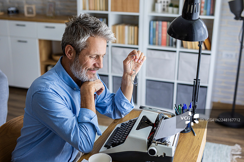舒适居家工作空间里，男子在打字机上写作图片素材