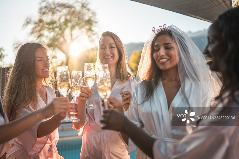 穿着丝绸睡袍的多元化女性朋友在泳池边图片素材