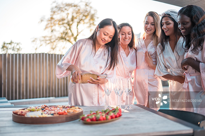 在多元化的单身女郎泳池聚会上倒香槟图片素材