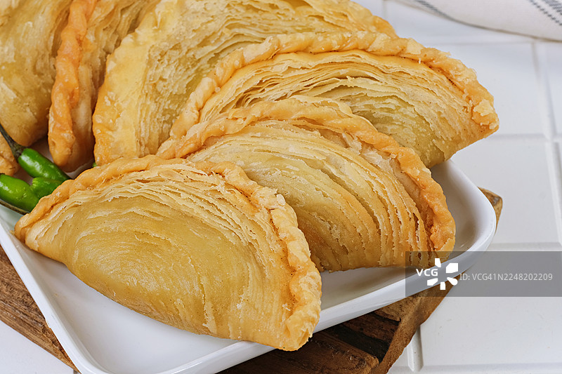 新鲜炸制的咖喱角糕点盛放在白色陶瓷盘中图片素材