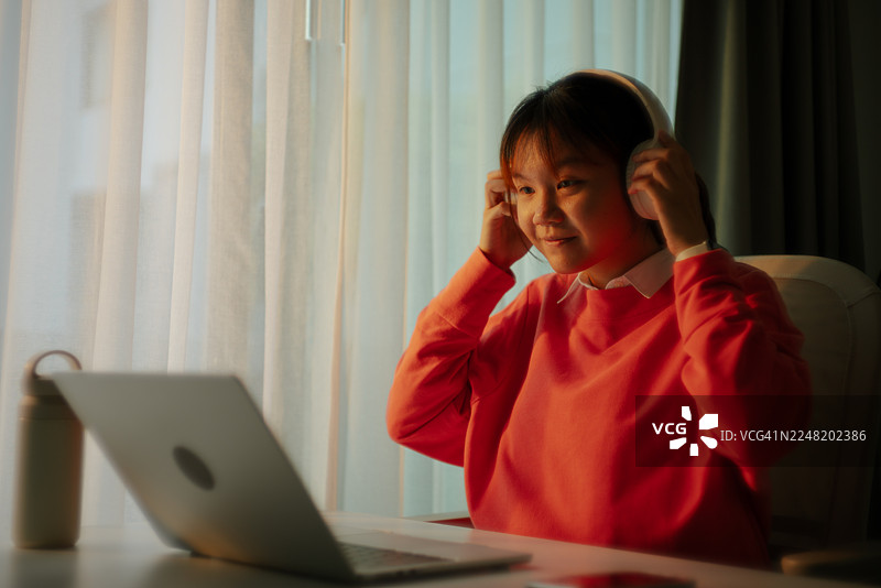 学生戴着耳机用笔记本电脑工作。图片素材