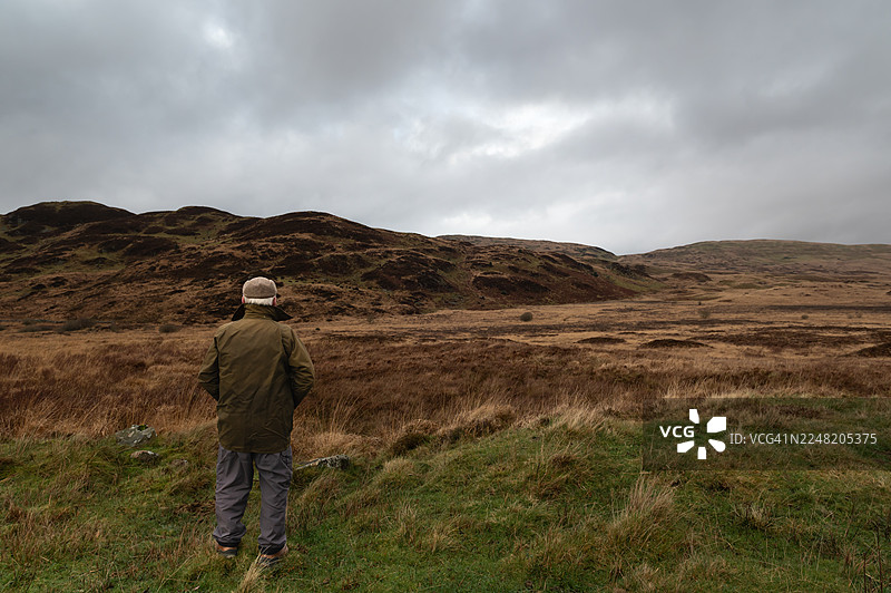 农民在远处的山坡上眺望牲畜图片素材