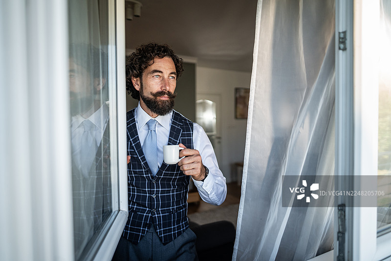 时尚商人一边喝咖啡一边沉思早晨的景色图片素材