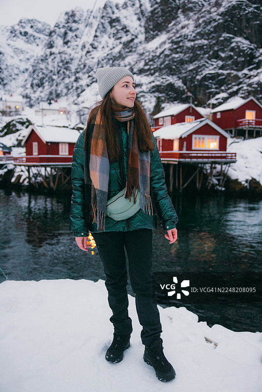 快乐的女人在渔村里走，背景是罗弗敦的红色罗布尔小屋图片素材