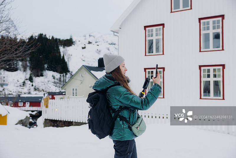 女子在罗弗敦群岛拍摄老城传统斯堪的纳维亚房屋的冬季美景图片素材