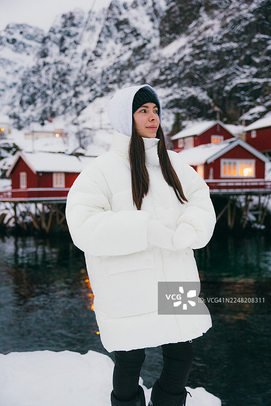 一位英俊的女士在罗弗敦岛的渔村散步，那里有红色的罗布尔房屋。图片素材