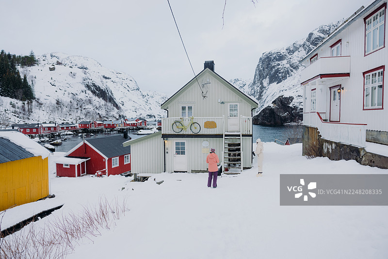 冬季，旅行者们在努斯峡湾镇行走，周围是传统的斯堪的纳维亚房屋图片素材